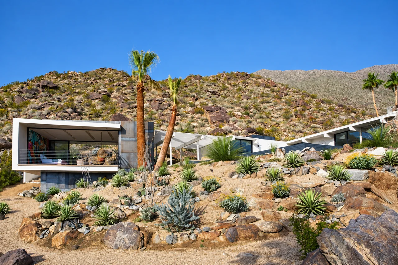 A modern desert house among palms, boulders and agaves in California