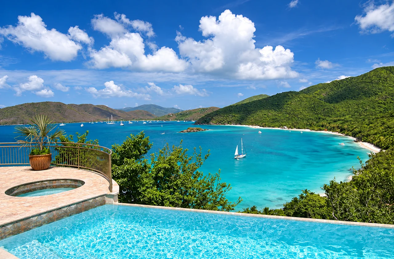 An infinity pool and round spa overlooking a turquoise bay with sailboats in St. John