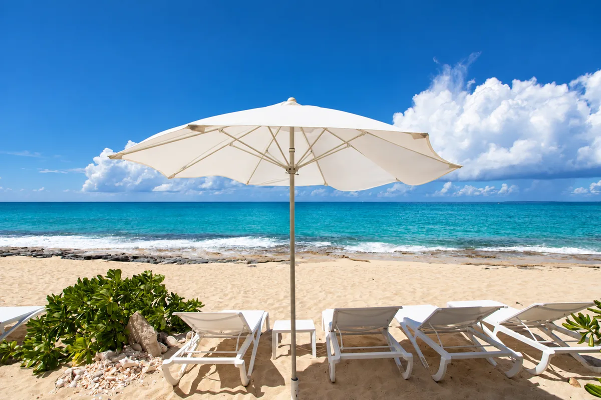 White loungers and a parasol beside turquoise Caribbean water in St. Martin