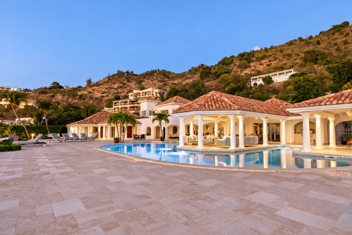 An illuminated villa and pool beneath the hillside at dusk in St. Martin