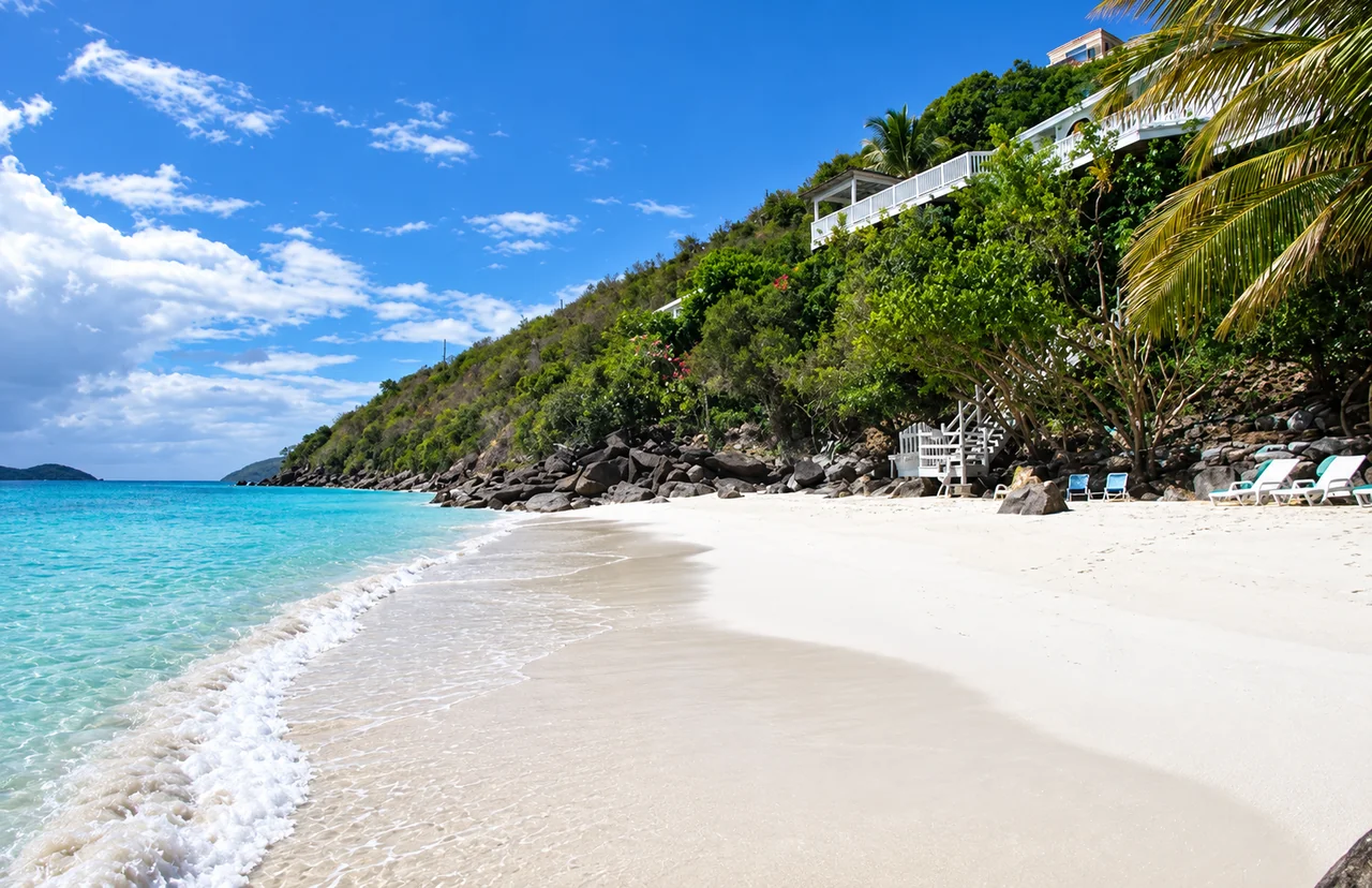 A sandy cove below hillside villa terraces with beach loungers in St. Thomas