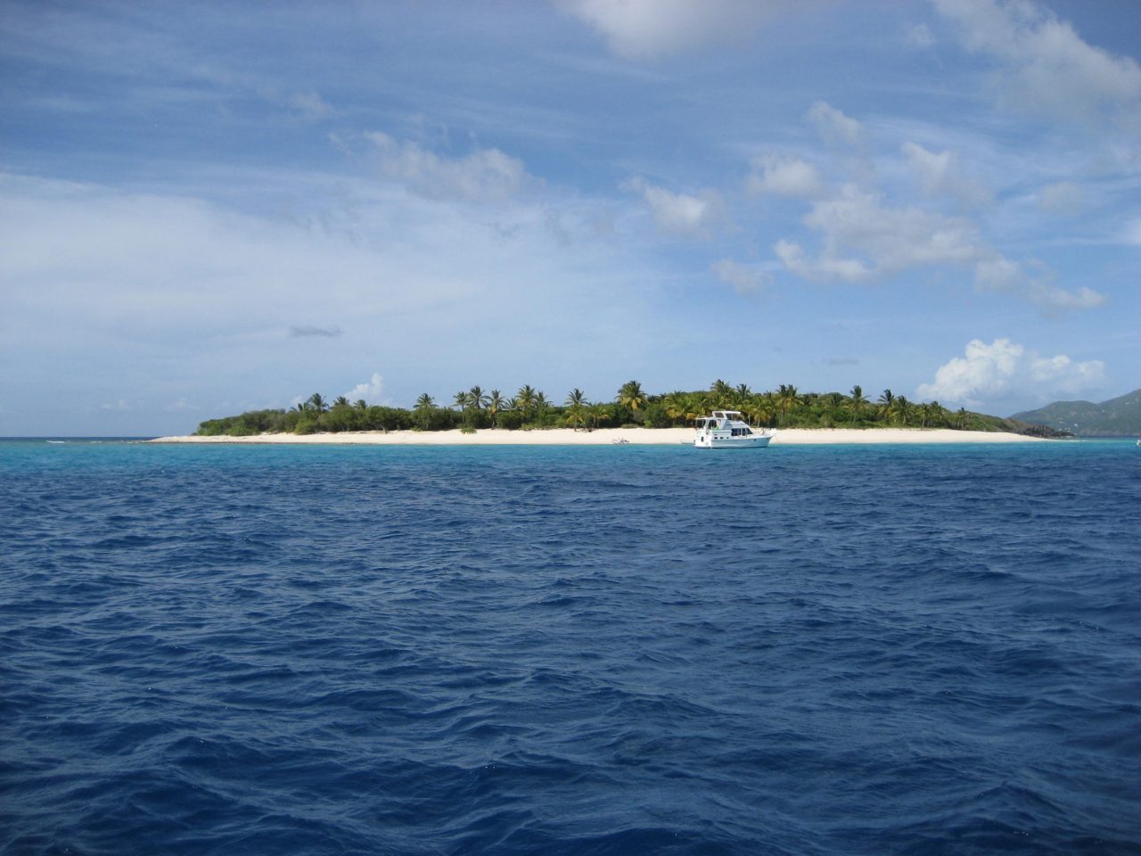 Boat anchored beside a palm-fringed island in the British Virgin Islands