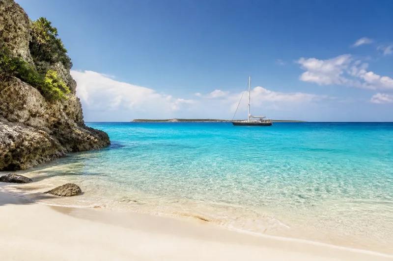 A sailing boat beyond a white-sand beach in Anguilla